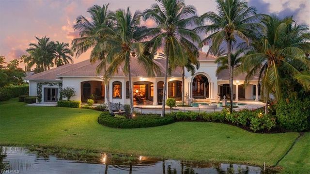 a view of a white house with a yard table and chairs