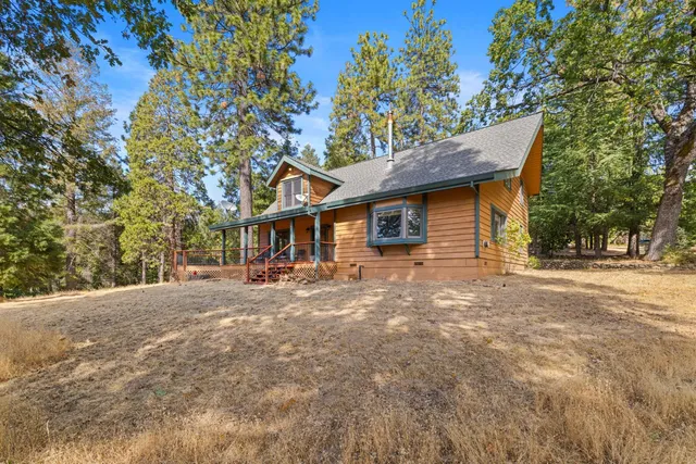 a large kitchen with kitchen island granite countertop lots of wooden cabinets stainless steel appliances a large window and a sink