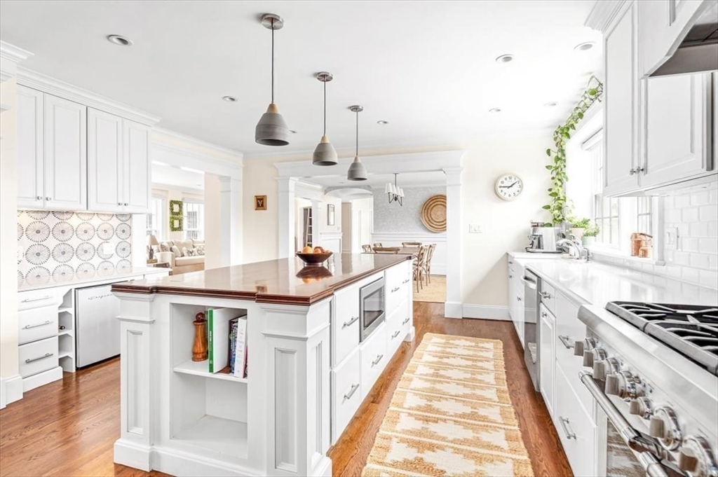 a large kitchen with kitchen island a stove a sink dishwasher and white cabinets with wooden floor