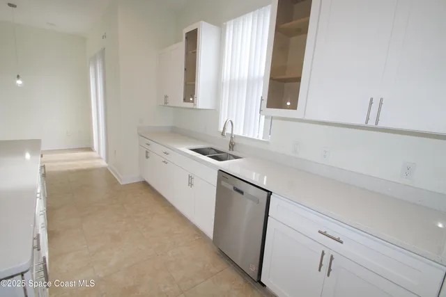 a kitchen with white cabinets and a window