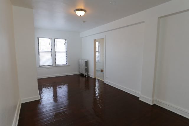 4608 North Beacon Street, Unit 3C Chicago, IL 60640 - Photo 8 of 12 an empty room with wooden floor and windows with curtains