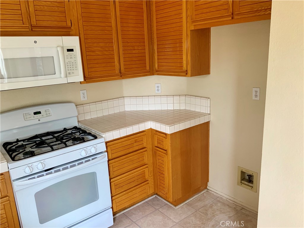 124 Cartier Aisle Irvine, CA 92620 - Photo 13 of 31 a kitchen with granite countertop cabinets and white appliances