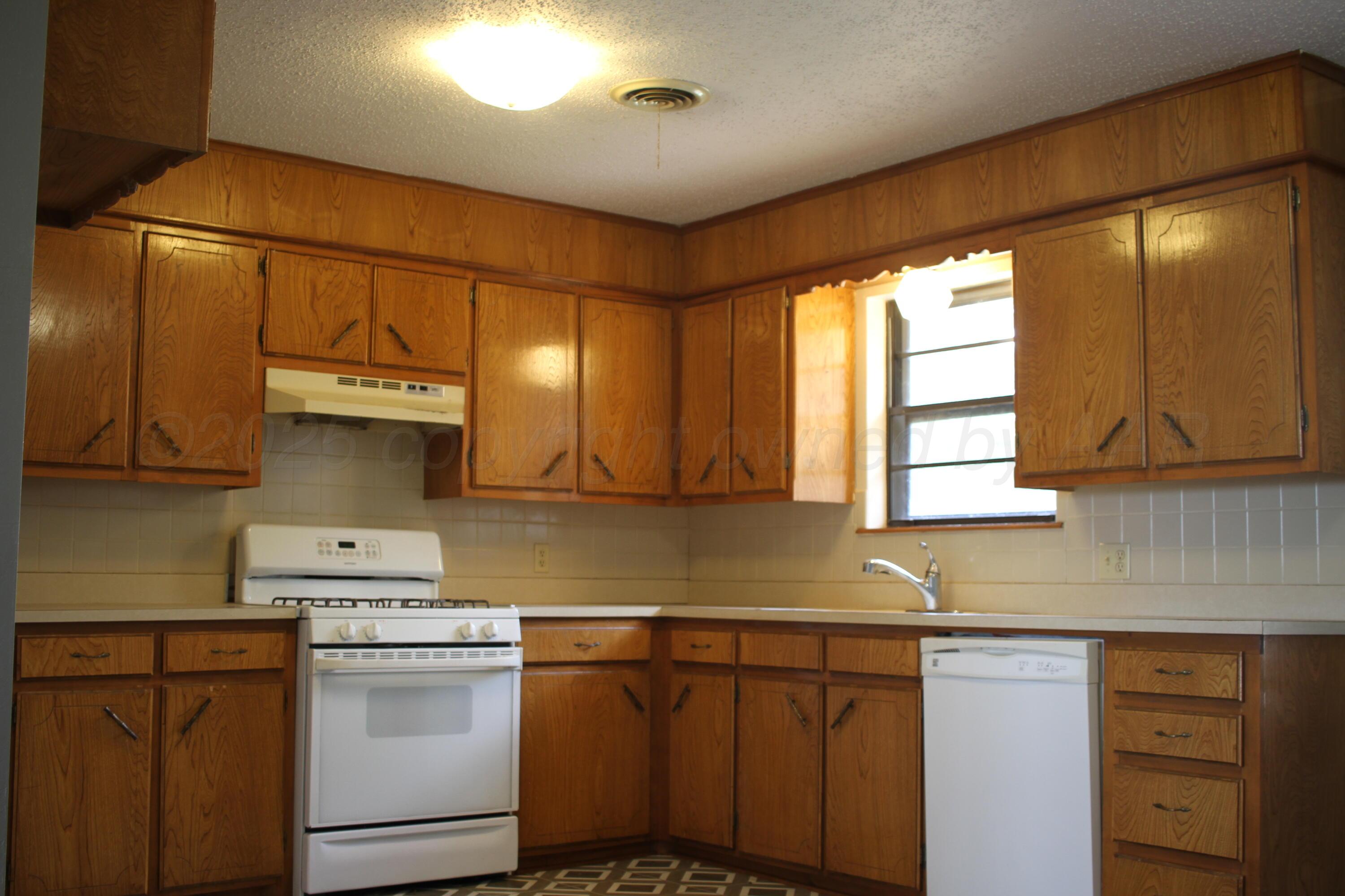 708 North Arizona Street Shamrock, TX 79079 - Photo 5 of 12 a kitchen with stainless steel appliances granite countertop a sink a stove and a refrigerator