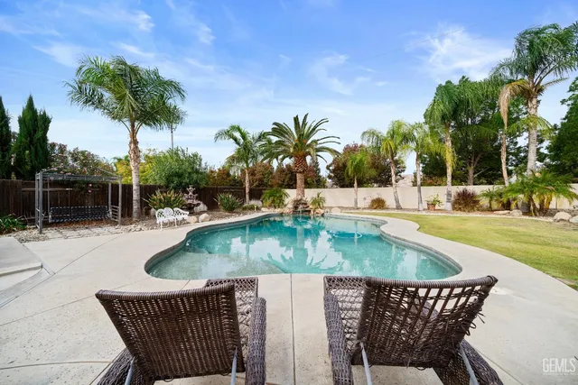 a view of a swimming pool with a patio and a yard