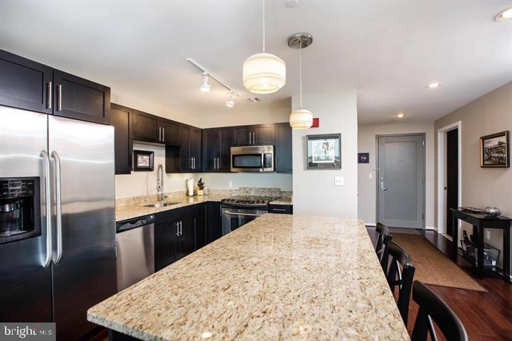 1200 Steuart Street, Unit 428 Baltimore, MD 21230 - Photo 8 of 53 a large kitchen with stainless steel appliances kitchen island granite countertop a stove refrigerator and cabinets