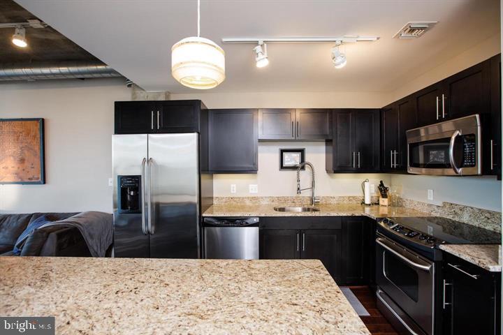 1200 Steuart Street, Unit 428 Baltimore, MD 21230 - Photo 9 of 53 a kitchen with stainless steel appliances wooden cabinets a sink and a stove