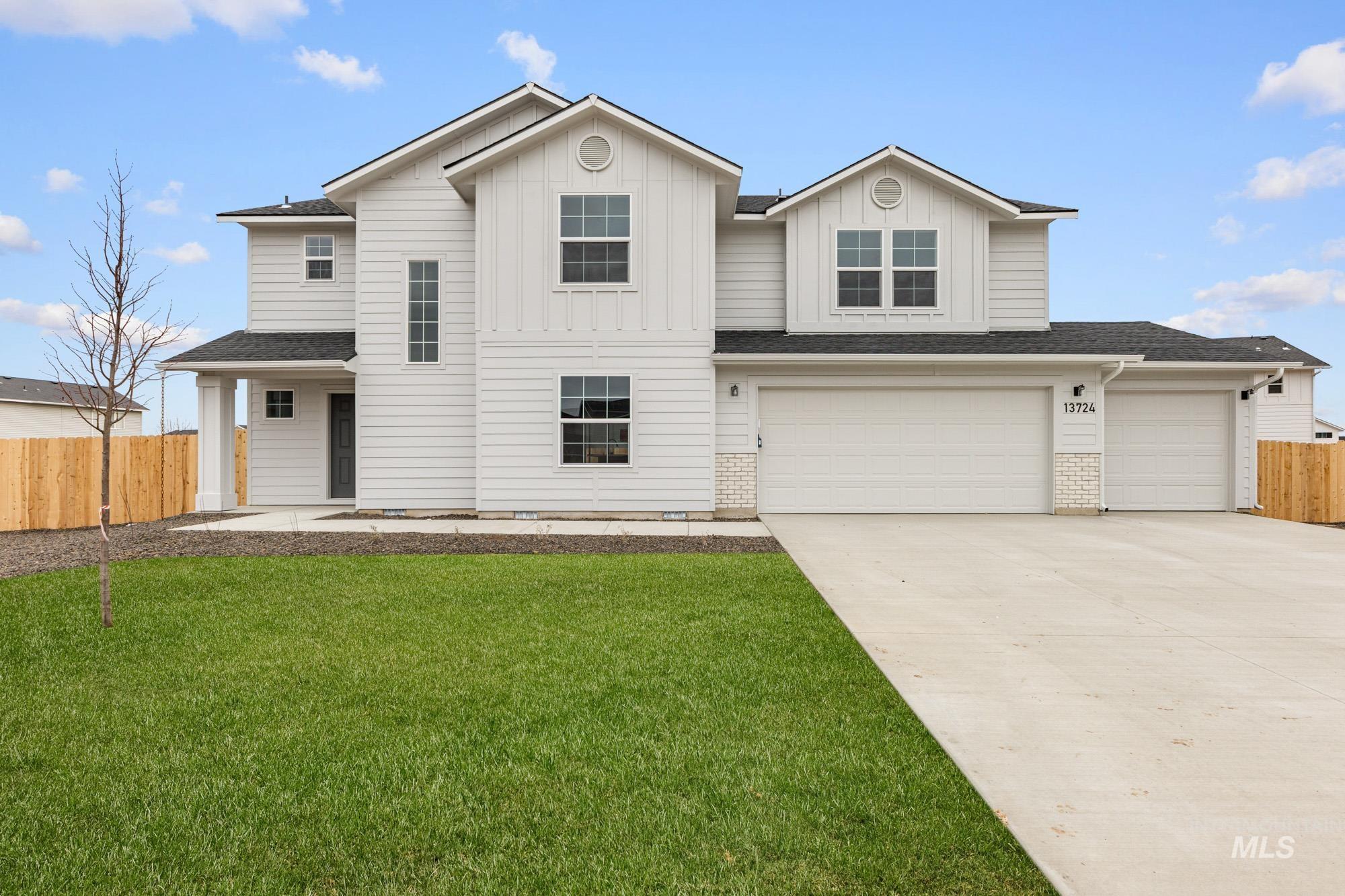 View of front of home with concrete driveway, board and batten siding, a shingled roof, and an attached garage