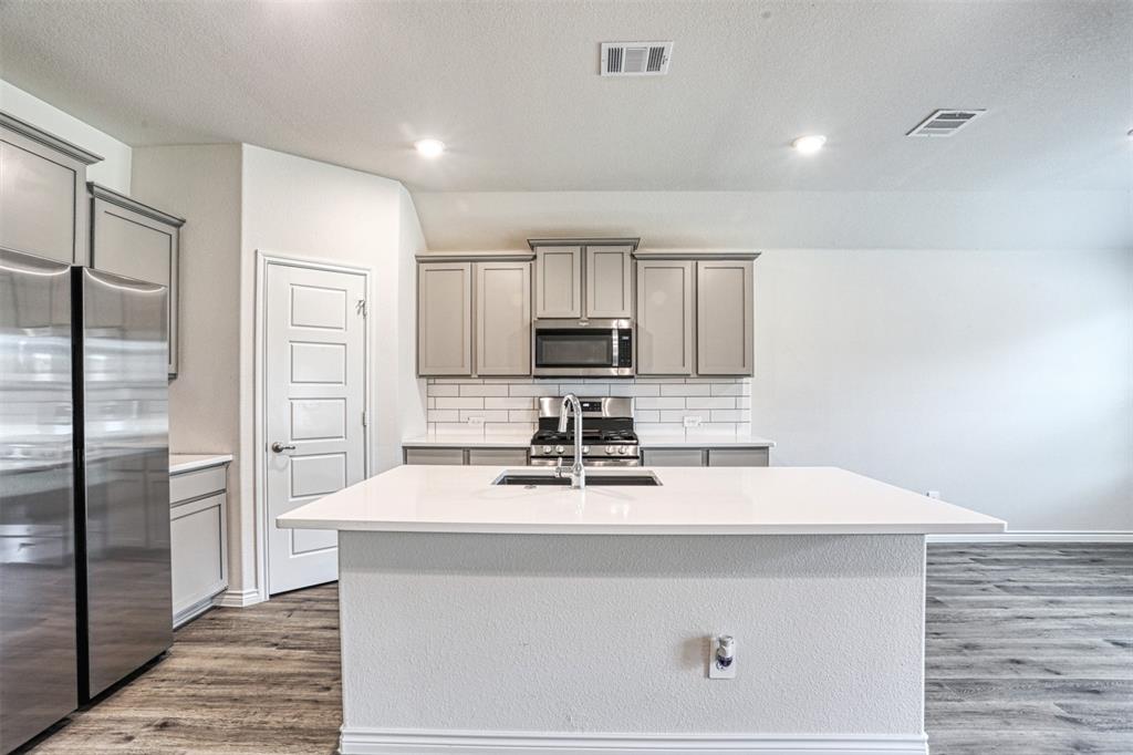 9813 Daisy Mae Aubrey, TX 76227 - Photo 3 of 28 a kitchen with a sink a refrigerator and cabinets