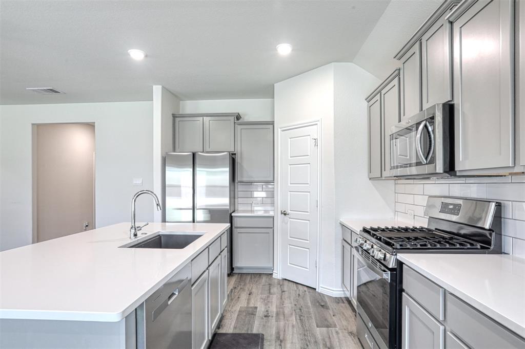 9813 Daisy Mae Aubrey, TX 76227 - Photo 6 of 28 a kitchen with stainless steel appliances granite countertop a sink stove and refrigerator