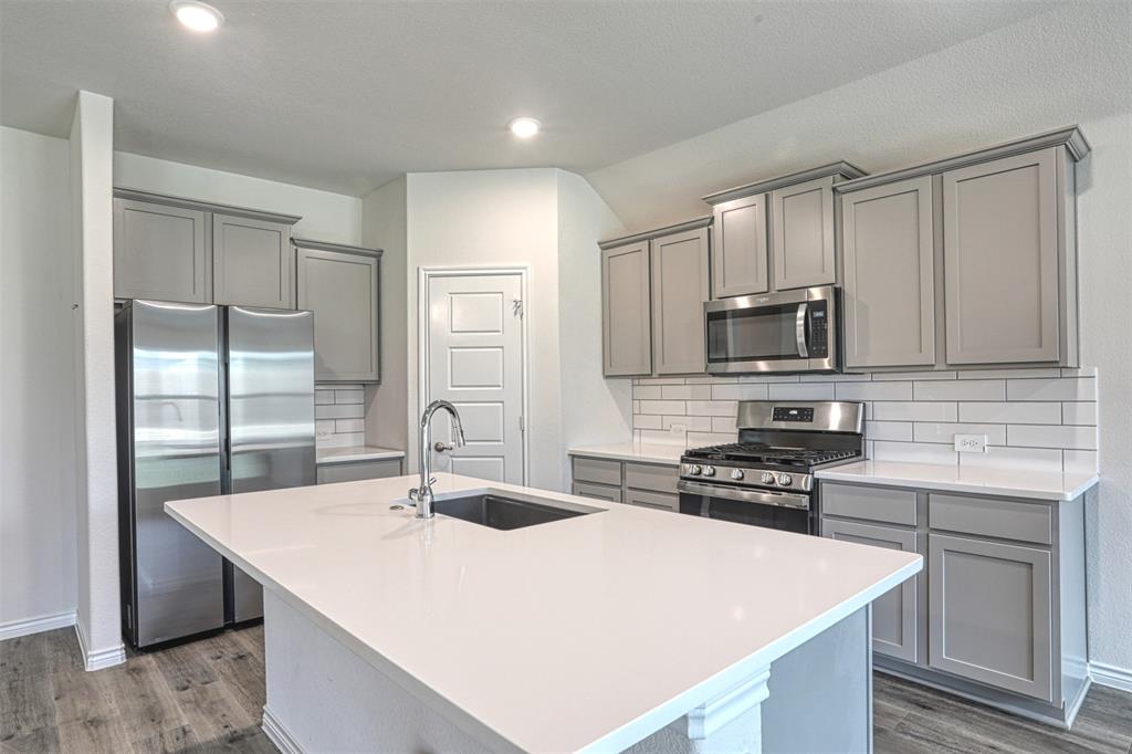 9813 Daisy Mae Aubrey, TX 76227 - Photo 7 of 28 a kitchen with stainless steel appliances a sink a stove a microwave and cabinets