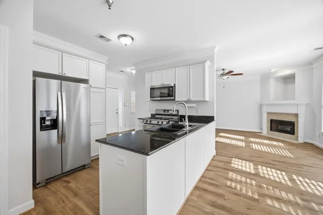 a kitchen with stainless steel appliances granite countertop a sink a stove and white cabinets