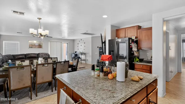 a kitchen with stainless steel appliances granite countertop kitchen island sink refrigerator dining table and chairs