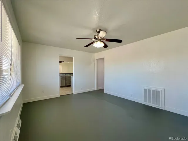 an empty room with a window and a ceiling fan
