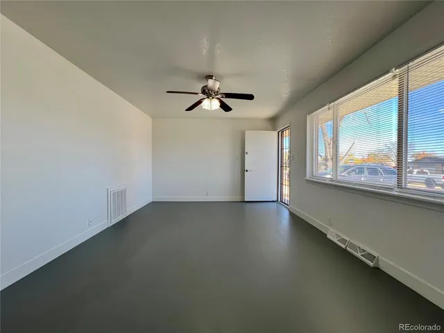 an empty room with a window and a ceiling fan