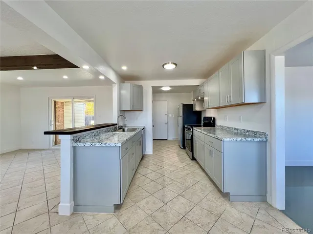 a large kitchen with stainless steel appliances kitchen island granite countertop a refrigerator and a stove