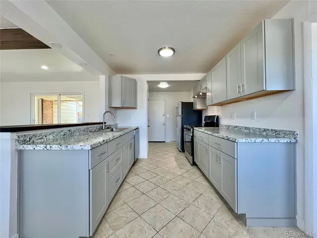 a large kitchen with stainless steel appliances kitchen island granite countertop a refrigerator and a stove top oven