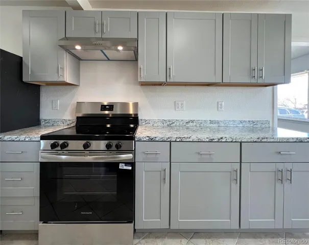 a kitchen with granite countertop white cabinets and a stove
