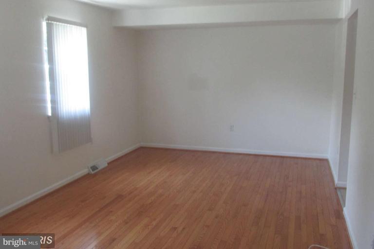 8024 Sandy Spring Road Laurel, MD 20707 - Photo 3 of 21 a view of an empty room with wooden floor and a window