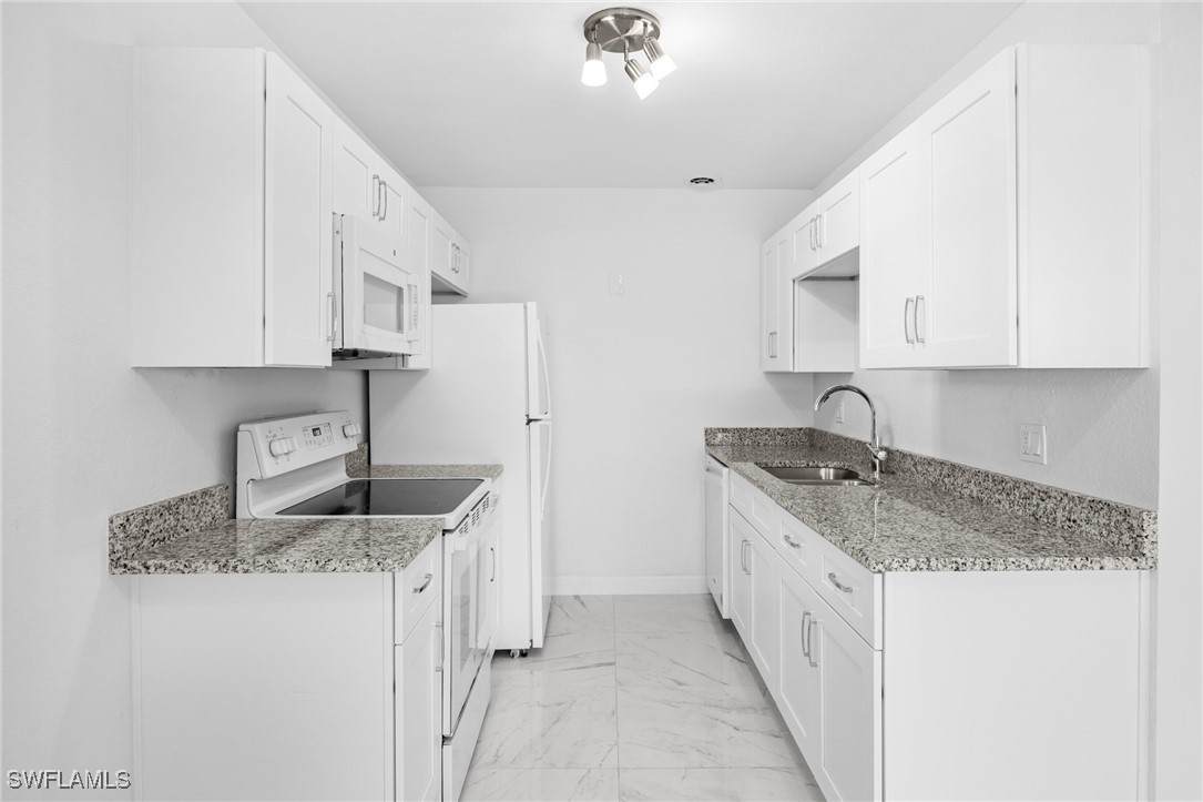 601 Periwinkle Way, Unit D1 Sanibel, FL 33957 - Photo 7 of 25 a kitchen with granite countertop a sink stove and cabinets