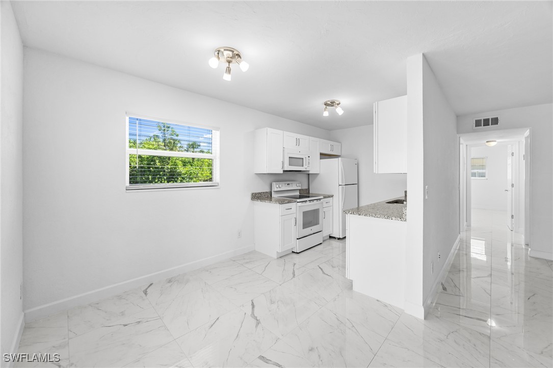 601 Periwinkle Way, Unit D1 Sanibel, FL 33957 - Photo 8 of 25 a kitchen with white cabinets and stainless steel appliances