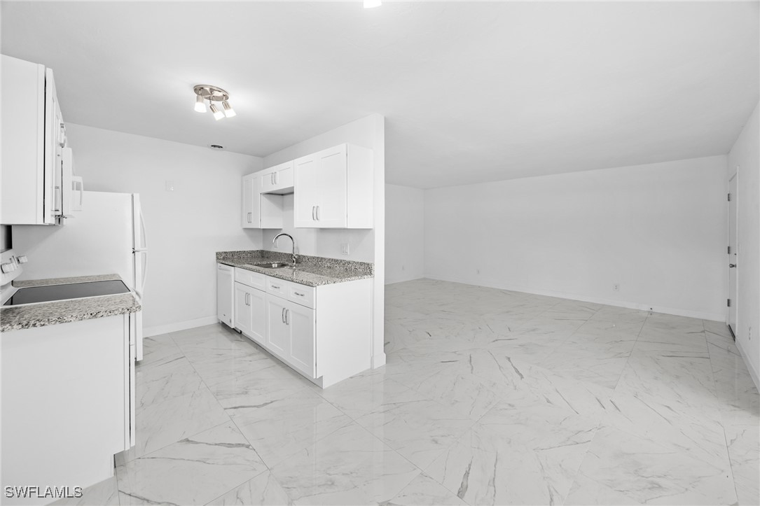 601 Periwinkle Way, Unit D1 Sanibel, FL 33957 - Photo 9 of 25 a kitchen with granite countertop white cabinets and white appliances