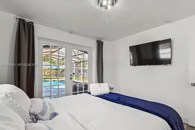 a bedroom with a bed tv and a window