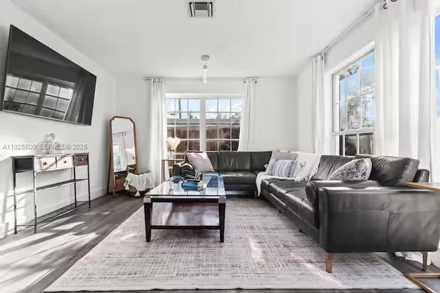 a living room with furniture a rug a flat screen tv and windows
