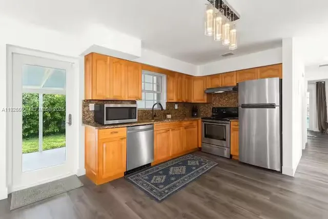 a kitchen with a refrigerator a stove cabinets and a dining table
