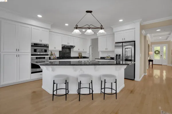 a kitchen with stainless steel appliances granite countertop a table chairs refrigerator and microwave