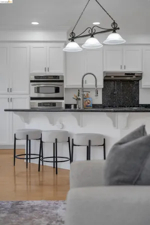 a kitchen with stainless steel appliances granite countertop a stove top oven a sink a dining table and chairs with wooden floor
