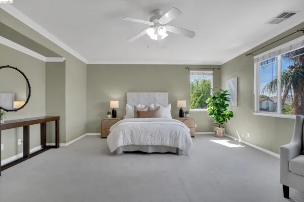a spacious bedroom with a bed a chandelier and a potted plant on the dresser