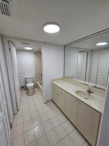 a bathroom with a sink a toilet and a large mirror