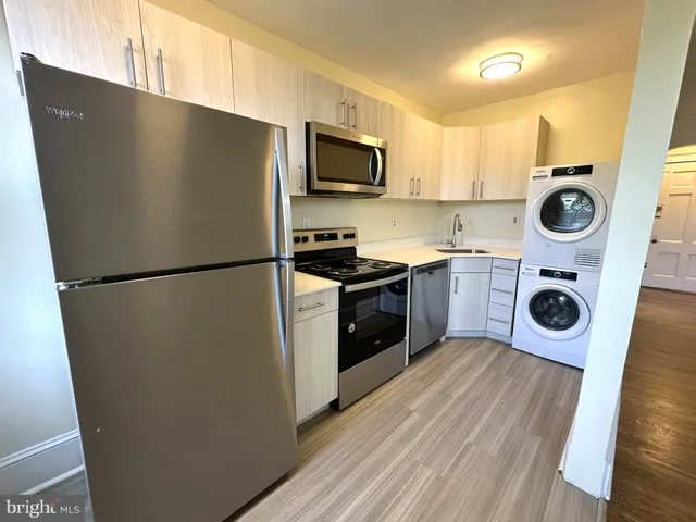 a kitchen with a refrigerator a stove top oven and wooden floor