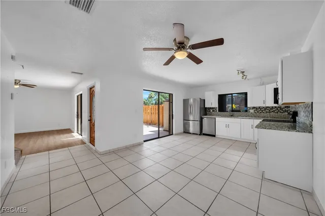 a view of a kitchen with a sink and dishwasher a refrigerator with white cabinets
