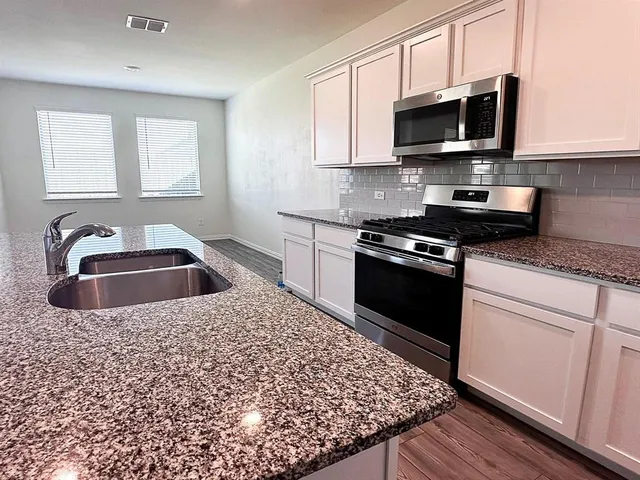 a kitchen with stainless steel appliances granite countertop a sink a stove a microwave and cabinets