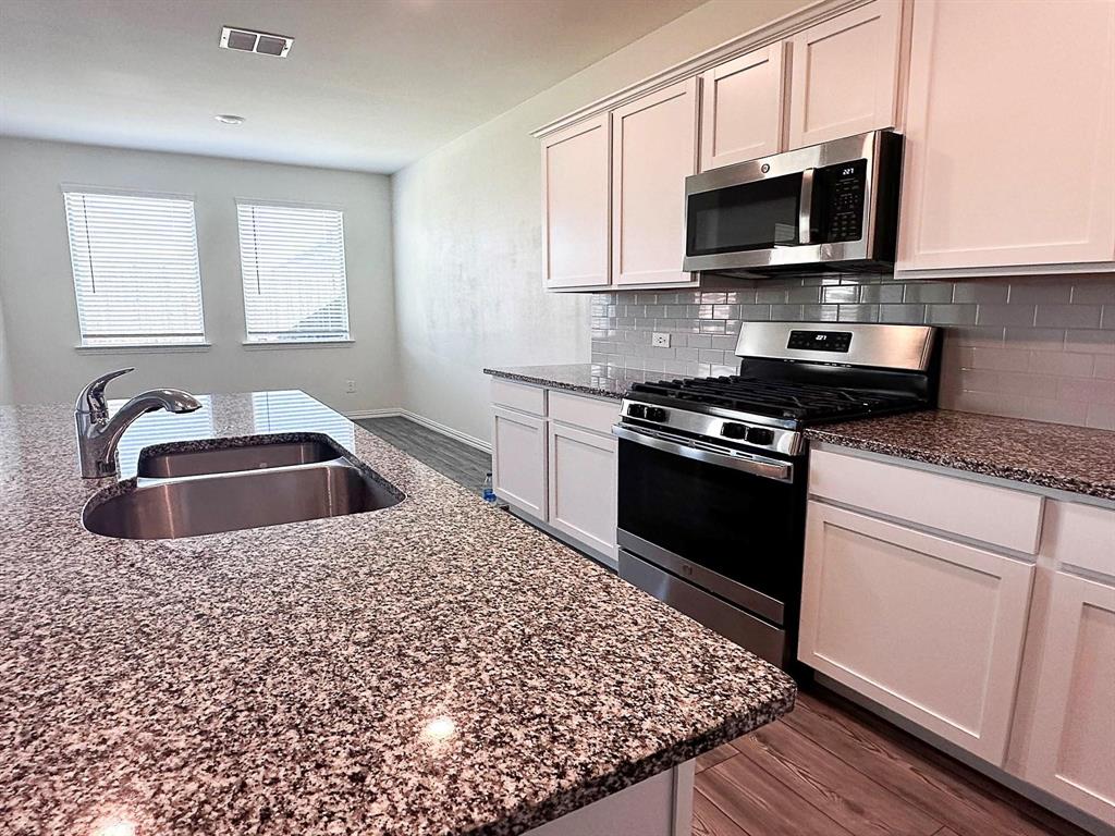 309 Hackberry Street Princeton, TX 75407 - Photo 13 of 28 a kitchen with sink a microwave and cabinets