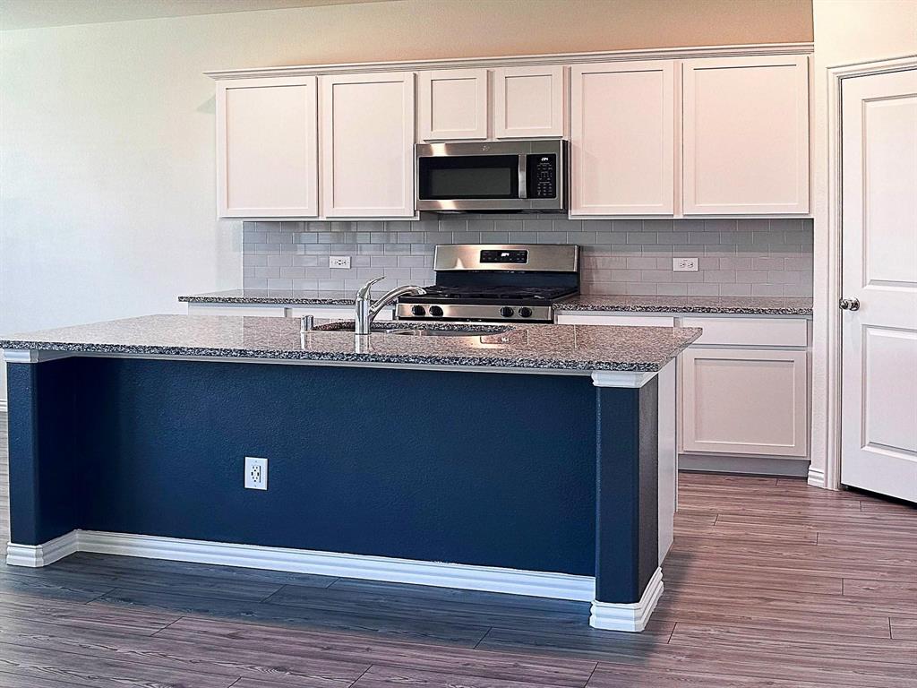 309 Hackberry Street Princeton, TX 75407 - Photo 14 of 28 a kitchen with stainless steel appliances granite countertop a sink a stove a microwave and cabinets