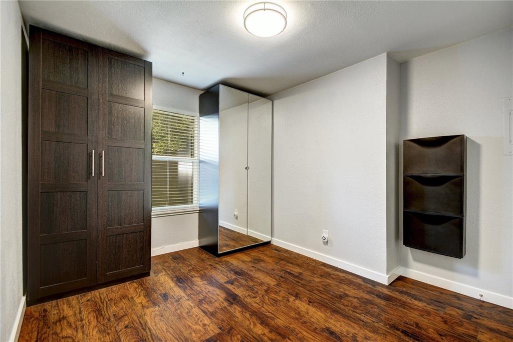 1120 Estes Avenue, Unit B Austin, TX 78721 - Photo 16 of 26 Unfurnished bedroom featuring dark wood-style flooring and a textured ceiling