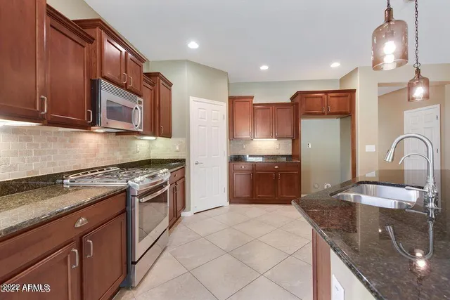 a kitchen with stainless steel appliances granite countertop a sink stove and refrigerator