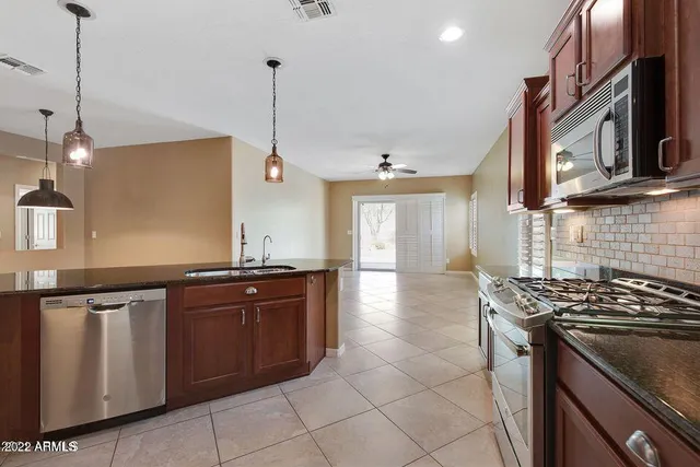 a kitchen with stainless steel appliances granite countertop a stove a sink and a microwave