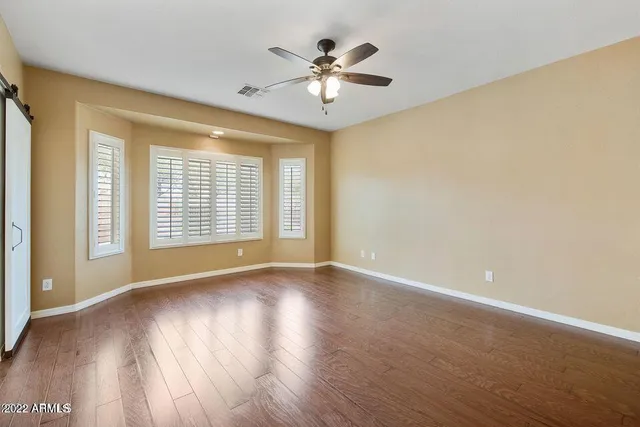 a view of an empty room with a window and wooden floor