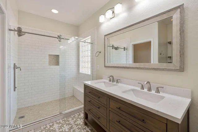a bathroom with a double vanity sink mirror and shower