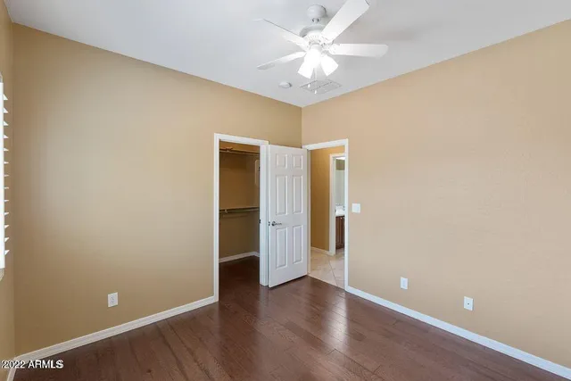 an empty room with wooden floor and a ceiling fan