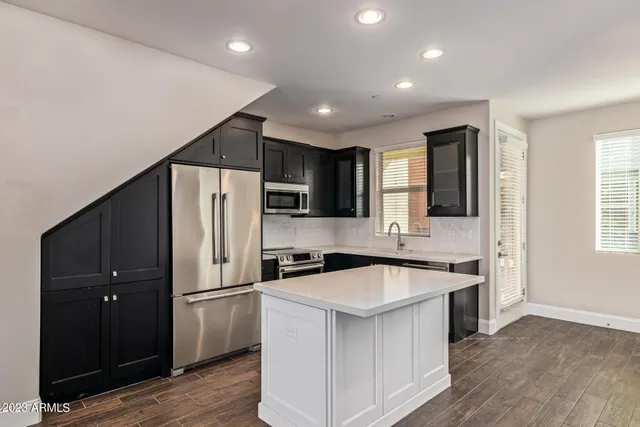 a kitchen that has a sink a center island stainless steel appliances cabinets and a window
