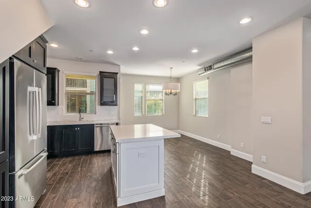 a large kitchen with stainless steel appliances granite countertop a refrigerator a sink dishwasher a stove and white countertops with wooden floor