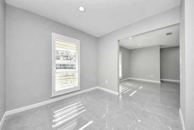 an empty room with windows and fan