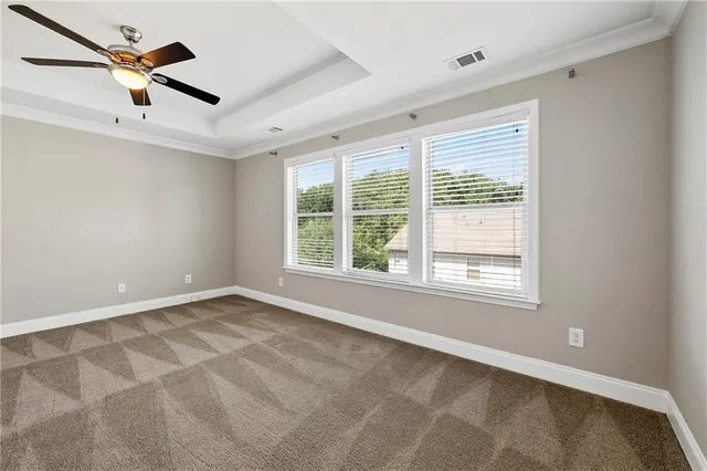 an empty room with ceiling fan and windows
