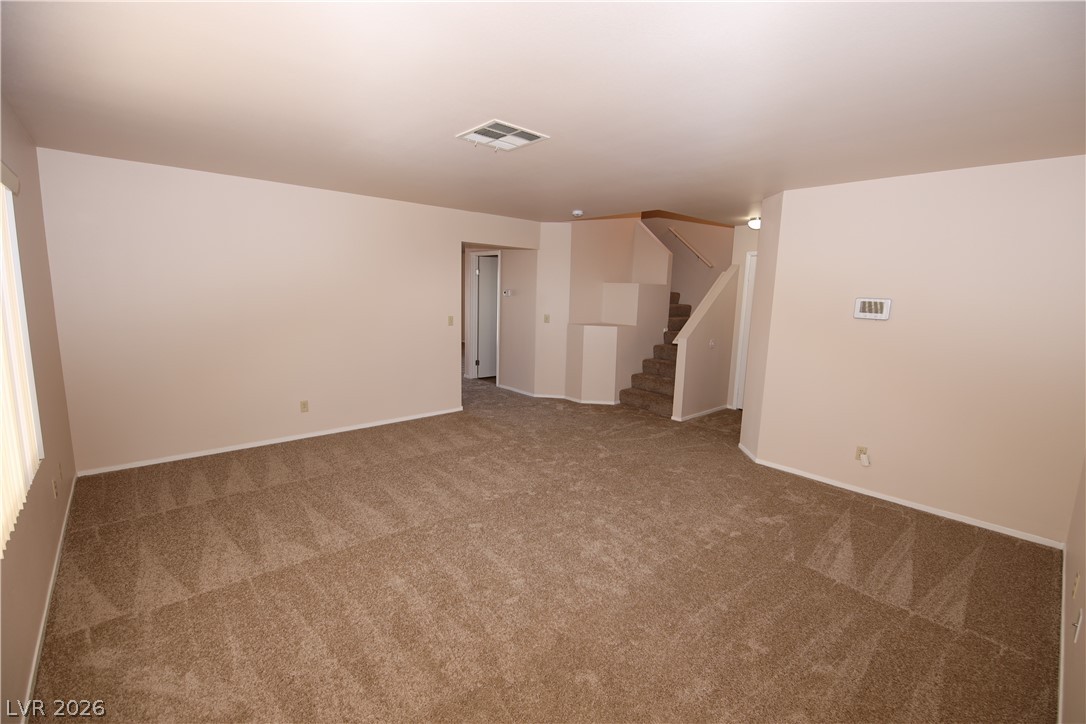 8220 Maplestar Road Las Vegas, NV 89128 - Photo 5 of 29 A spacious, neutral-toned living area features plush carpeting and a carpeted stairway leading to the upper level.