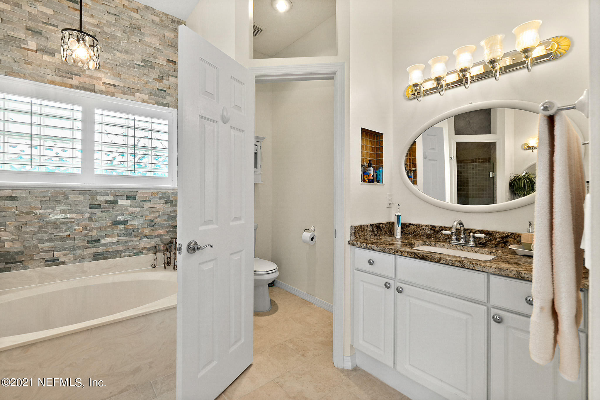 9269 July Lane St. Augustine, FL 32080 - Photo 44 of 105 a bathroom with a sink a large mirror and a bathtub next to a window