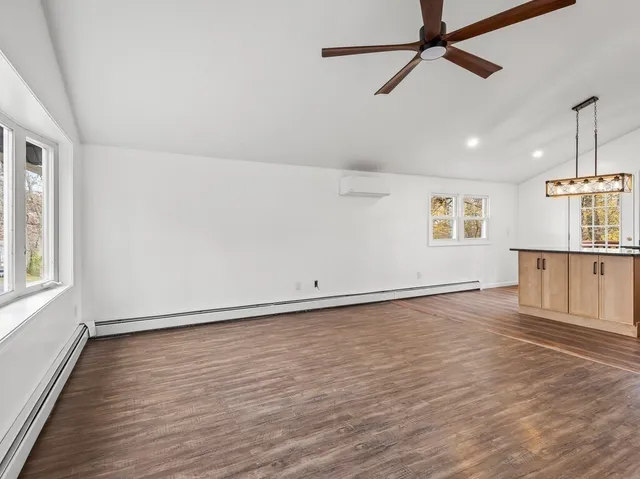 an empty room with wooden floor fan and windows